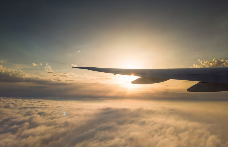 Airplane window view to the clouds and sunset