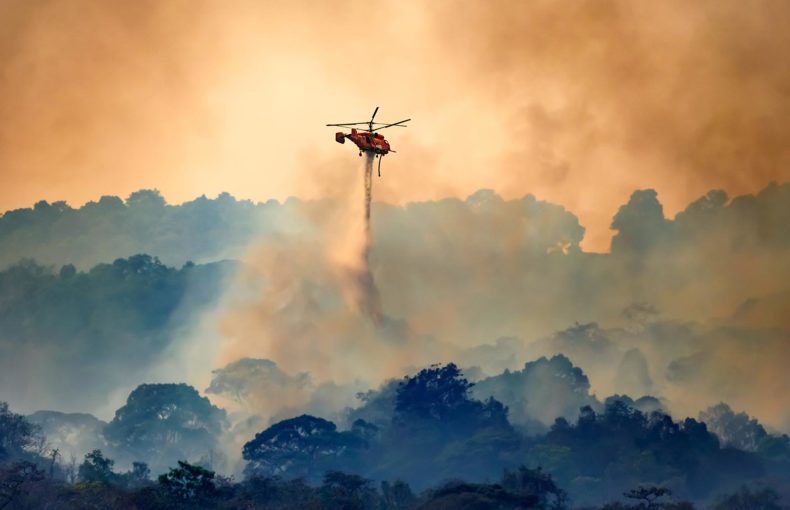 Firefighting helicopter dropping water on forest fire